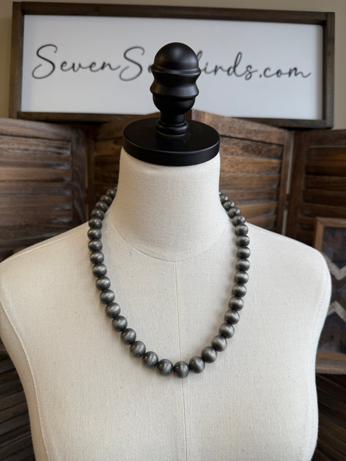 12 mm dark pearl bead necklace on mannequin, black clasp