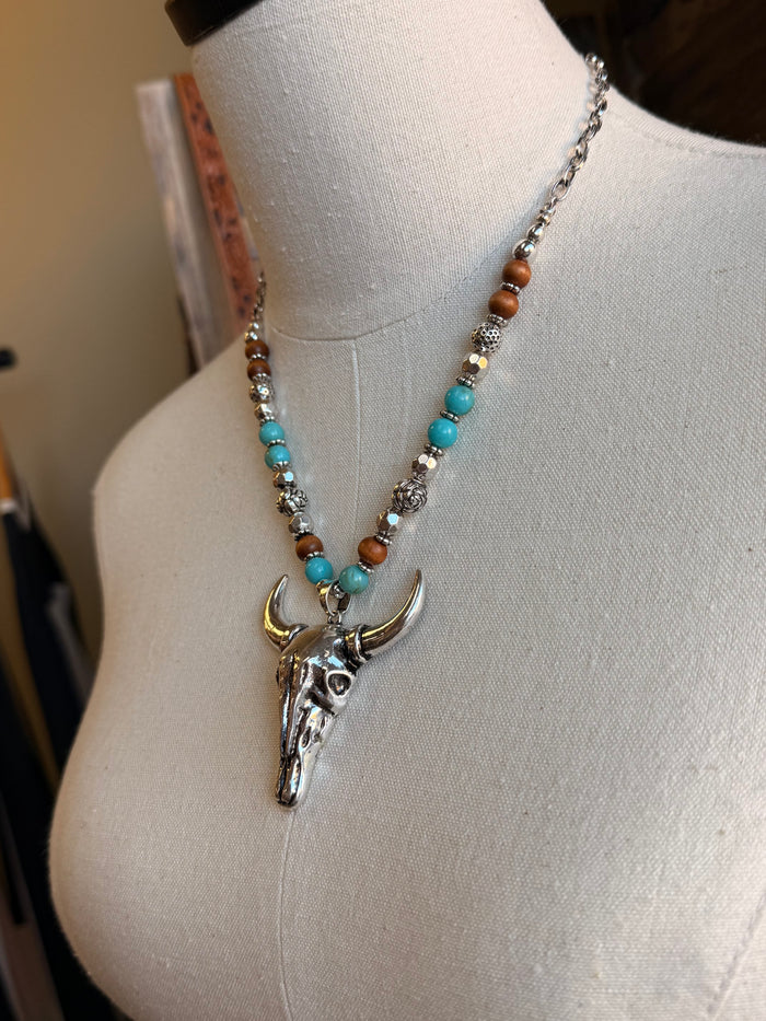 Close-up beaded cow skull pendant necklace with turquoise center and silver-tone skull