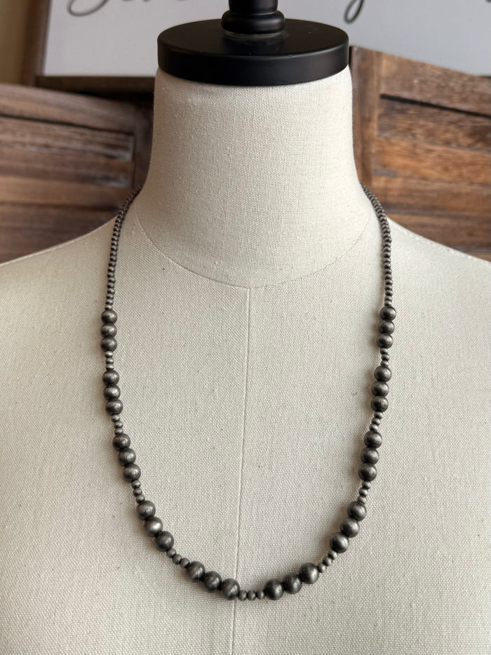 Graduated dark pearl bead necklace, close-up of evenly spaced beads
