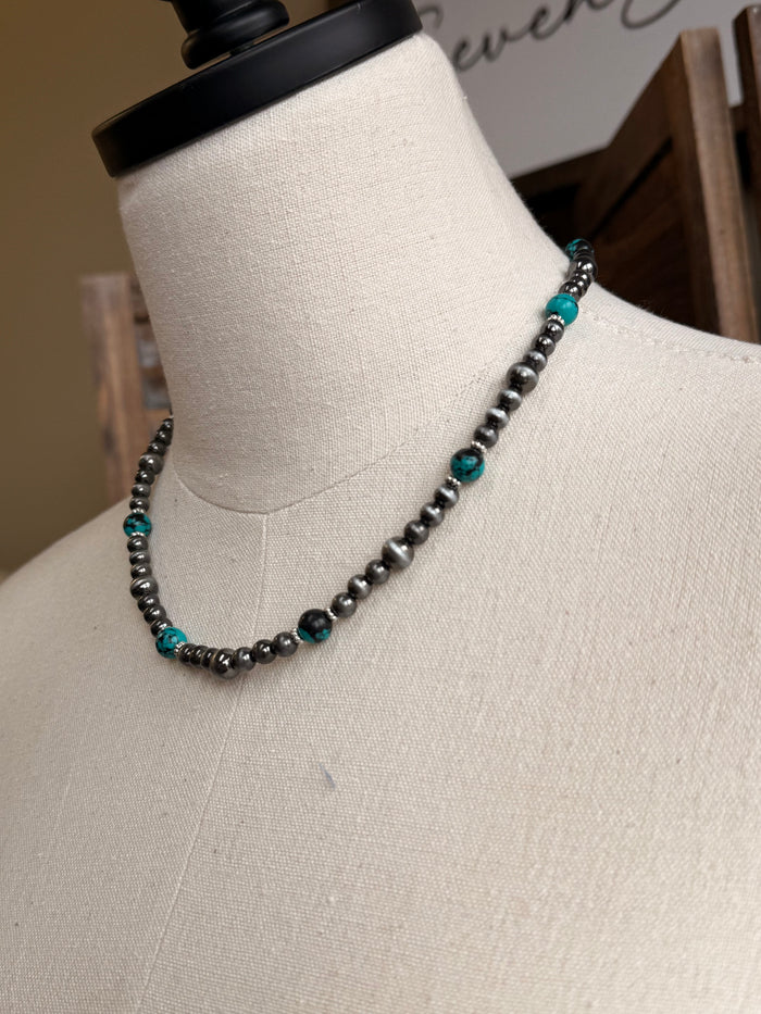 Turquoise stone bead necklace with silver-tone links, angled close-up