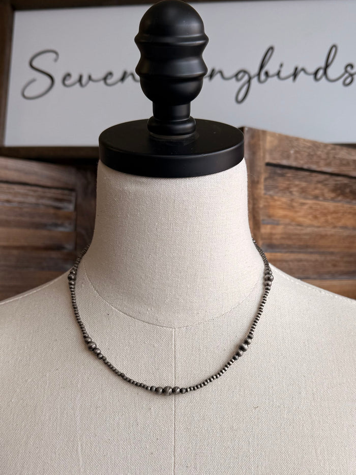 Graduated silver pearl necklace with small-to-large pearls along a metal chain, front view