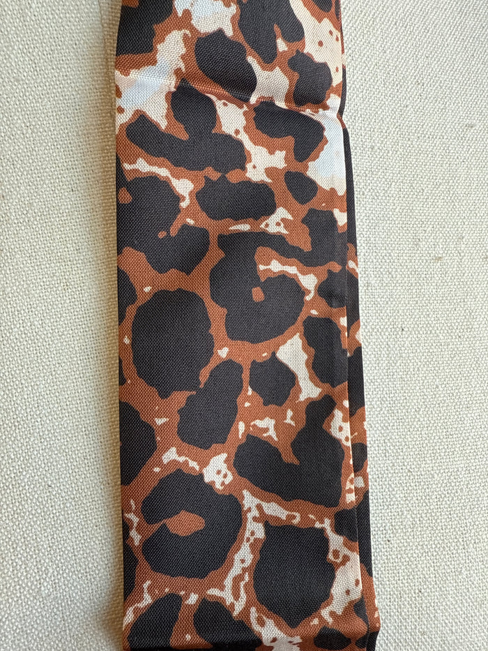 Animal print twilly scarf close-up with brown, tan, and black pattern on fabric