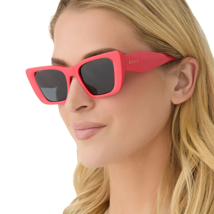 on model - female wearing diff eyewear aura square sunglasses with a sunset red frame and grey polarized lenses angled view