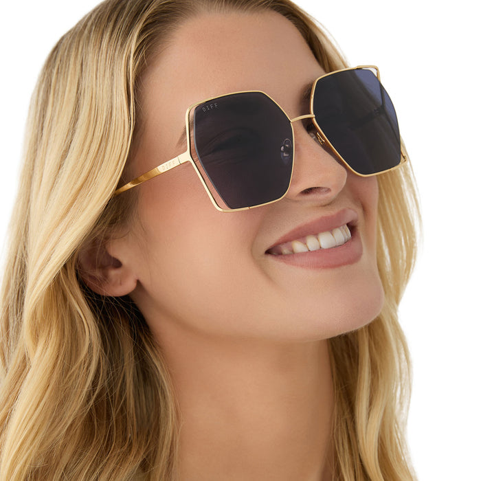 on model - female wearing diff eyewear featuring the donna iv square sunglasses with a gold frame and midnight blue polarized lenses angled view