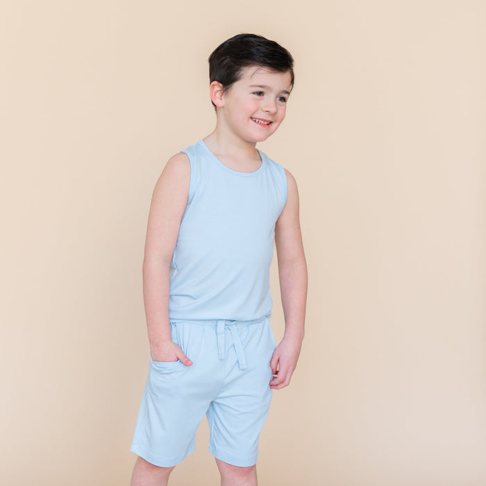 Smiling boy standing with one hand in the pocket of the Drawstring Short in Breeze paired with a matching tank top