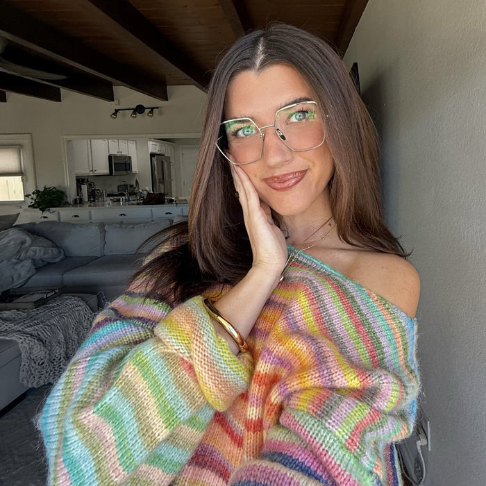 customer content - Sara Joy brunette influencer wearing rainbow striped knit off the shoulder sweater with silver wire frame eyeglasses