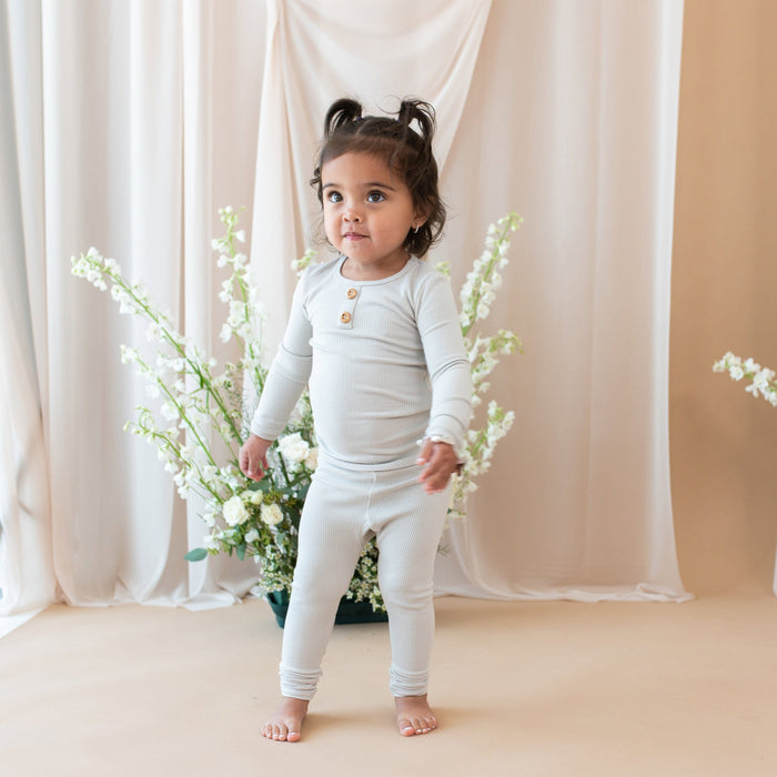 Toddler wearing Kyte Baby Ribbed Henley Set with wooden button placket in Oat