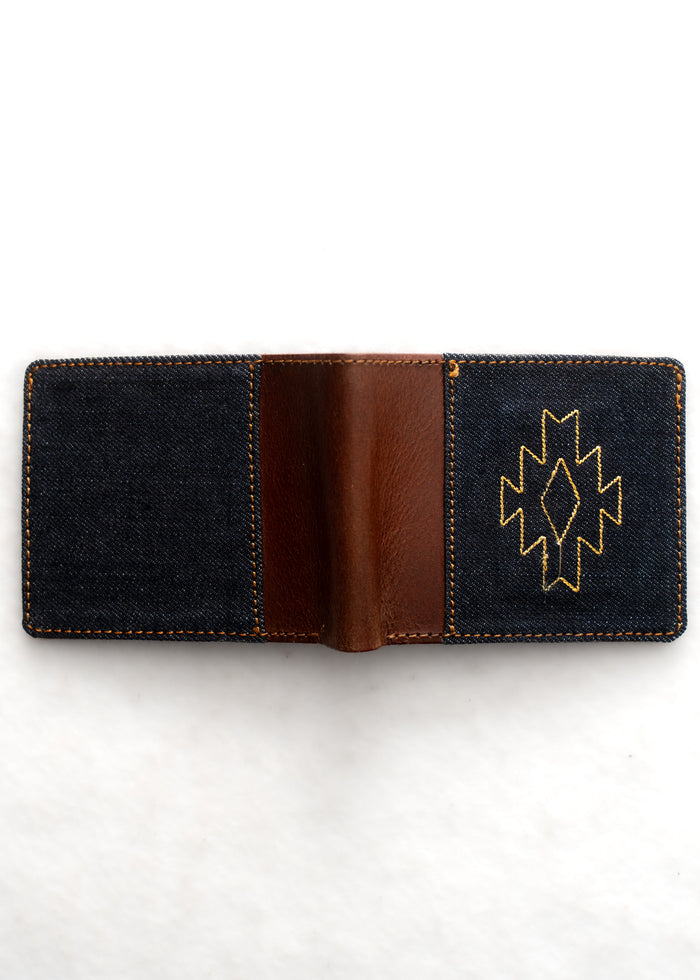 Open denim wallet with brown leather interior and yellow geometric stitching on the right side, against a white background.