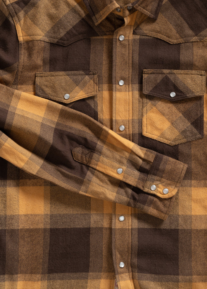 Brown and yellow plaid shirt with snap buttons and chest pockets, neatly laid out with one sleeve folded across the front.