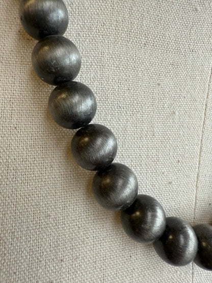 12 mm dark pearl bead necklace on light fabric