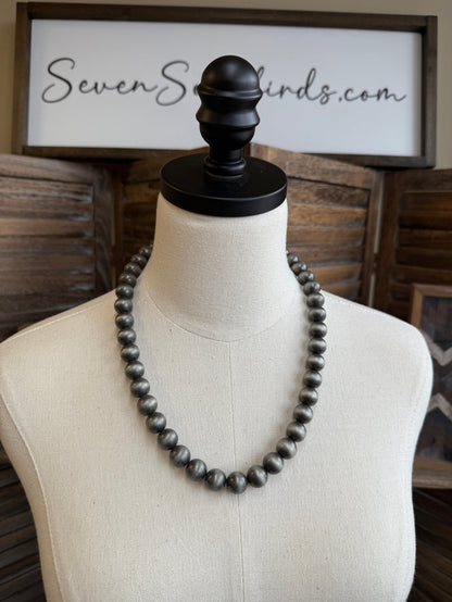 12 mm dark pearl bead necklace on mannequin, black clasp