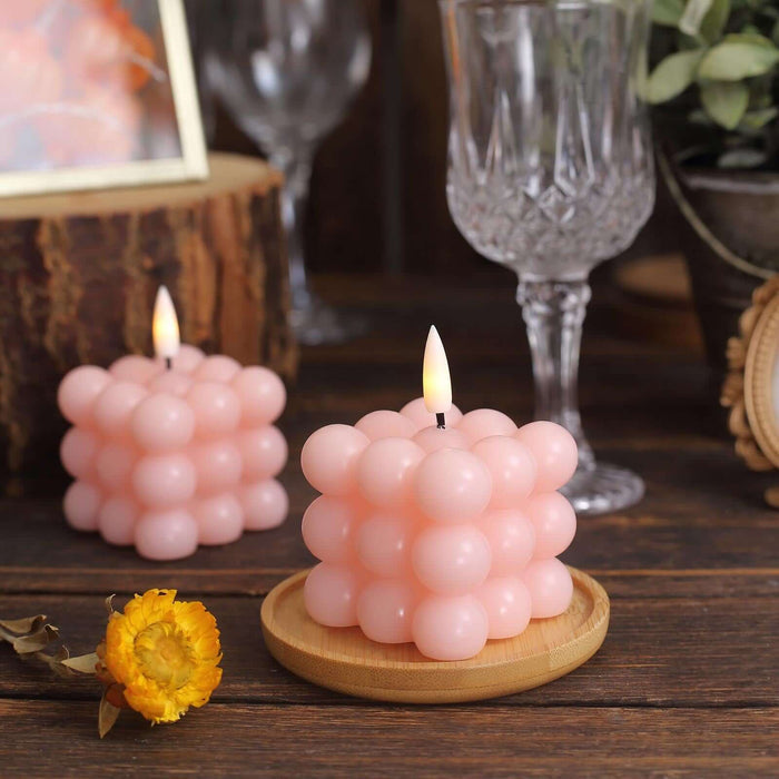 Pink bubble candle on a wooden tray, surrounded by decor elements.