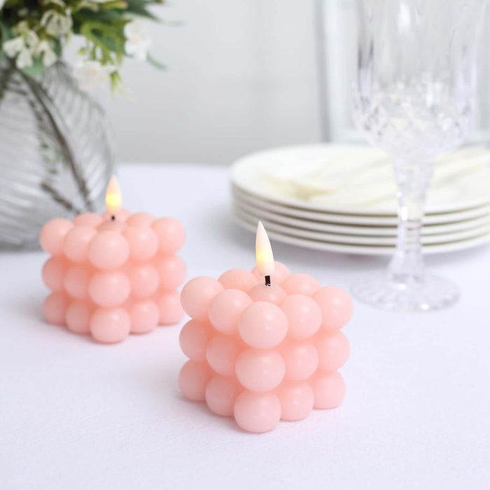 Pink bubble candle set on a table with elegant dinnerware.
