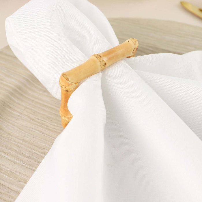 White napkin with bamboo ring on a wooden plate.