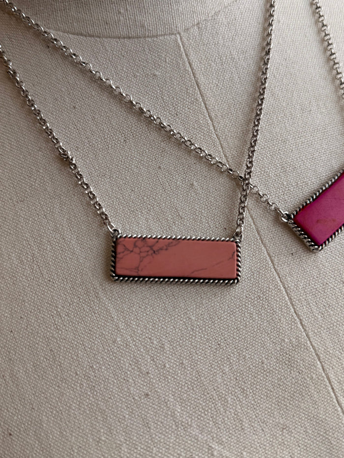 Stone bar necklace with brown rectangular pendant on silver chain; magenta pendant visible