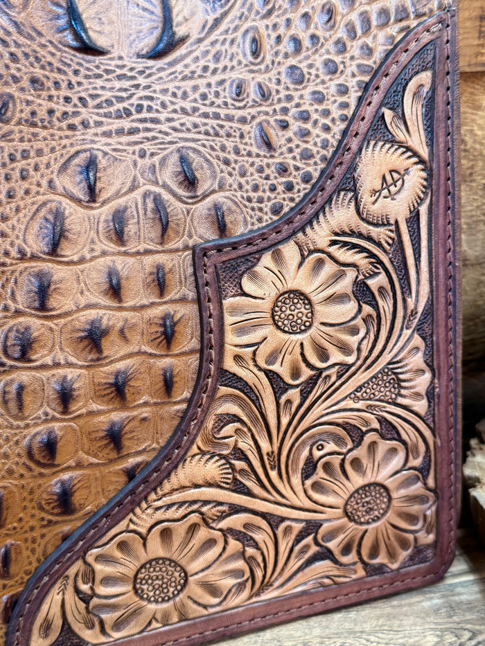 Embossed notebook folder close-up with stitched border and engraved flower panel