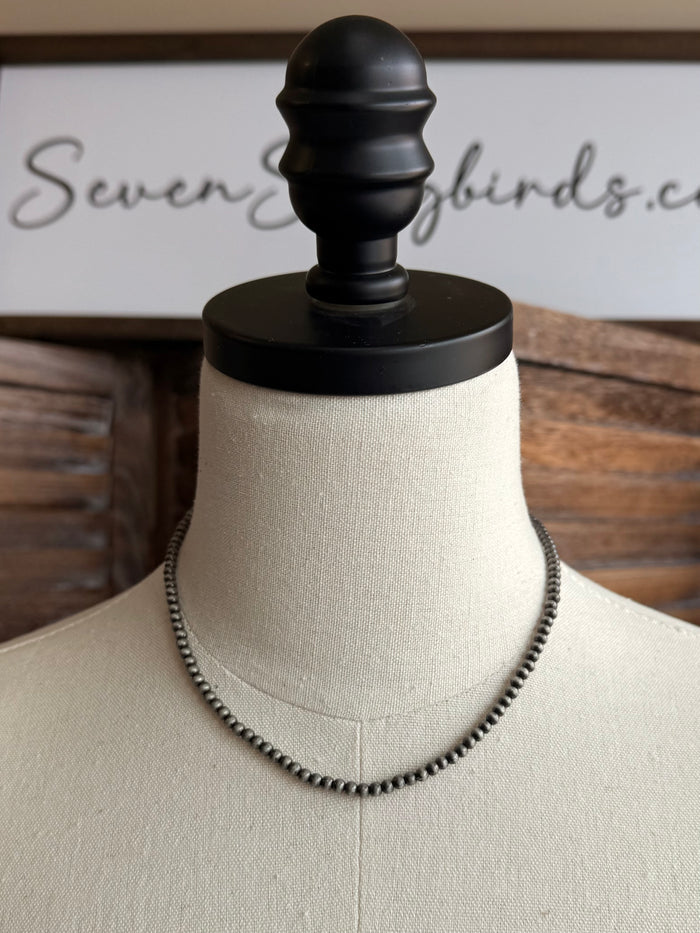 Tiny pearl beaded choker necklace with small round pearls on display stand