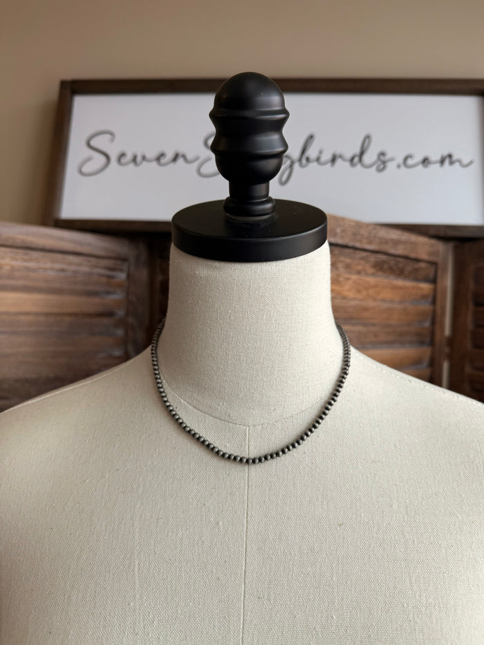 Tiny pearl beaded necklace on mannequin bust, close-fitting choker length