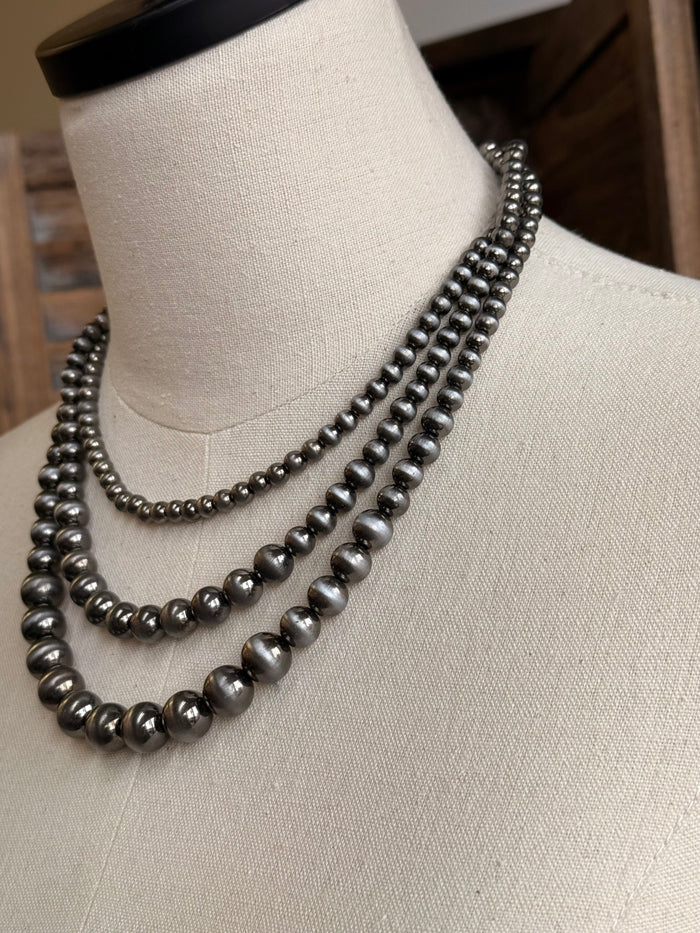 Triple-layer pearl necklace close-up with silver-toned bead rows