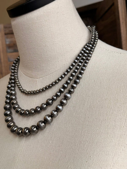 Triple-layer pearl necklace close-up with silver-toned bead rows