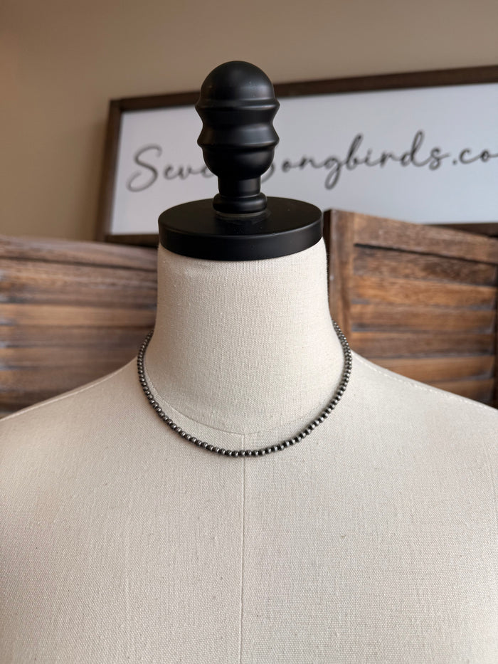 Silver-toned beaded double-strand necklace centered on mannequin
