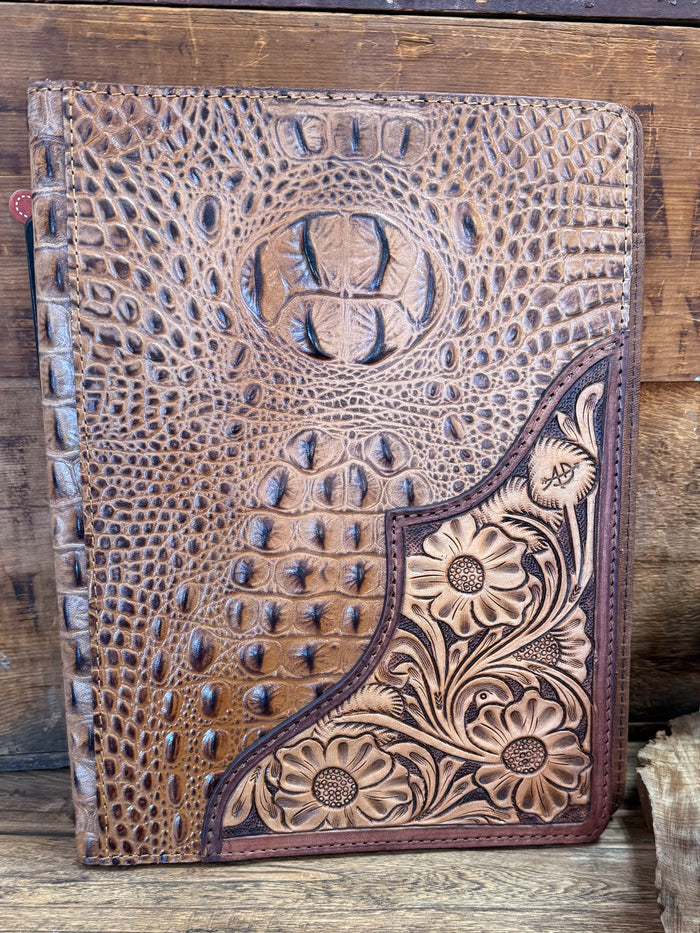 Crocodile-embossed notebook folder with circular crest and engraved floral corner