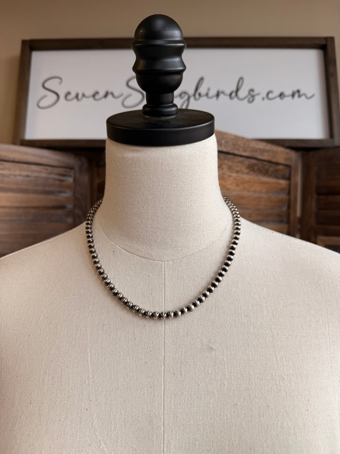 18-inch pearl necklace with dark 5mm round beads, draped on mannequin