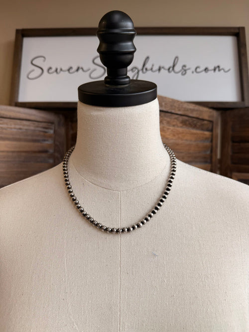 18-inch pearl necklace with dark 5mm round beads, draped on mannequin