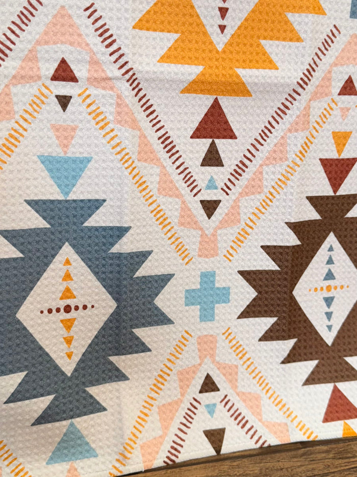 Cream Aztec towel close-up with blue and orange diamonds, triangles, and plus sign shapes.
