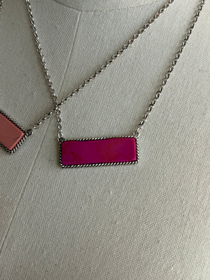 Stone bar necklace with purple rectangular pendant on silver chain; orange pendant partly visible