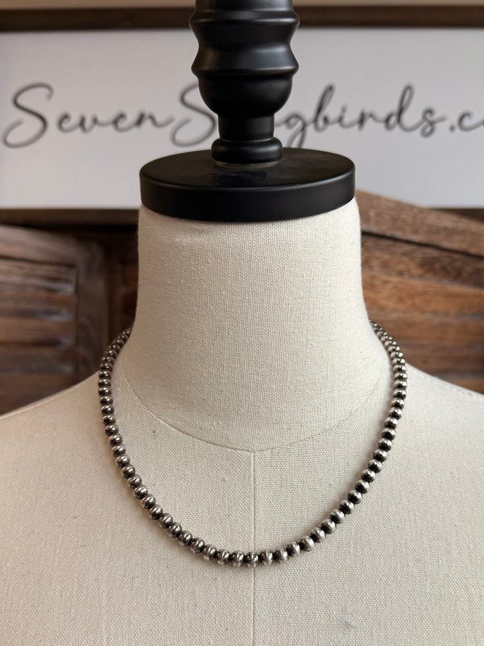 18-inch pearl necklace with dark 5mm round pearls, full length on display