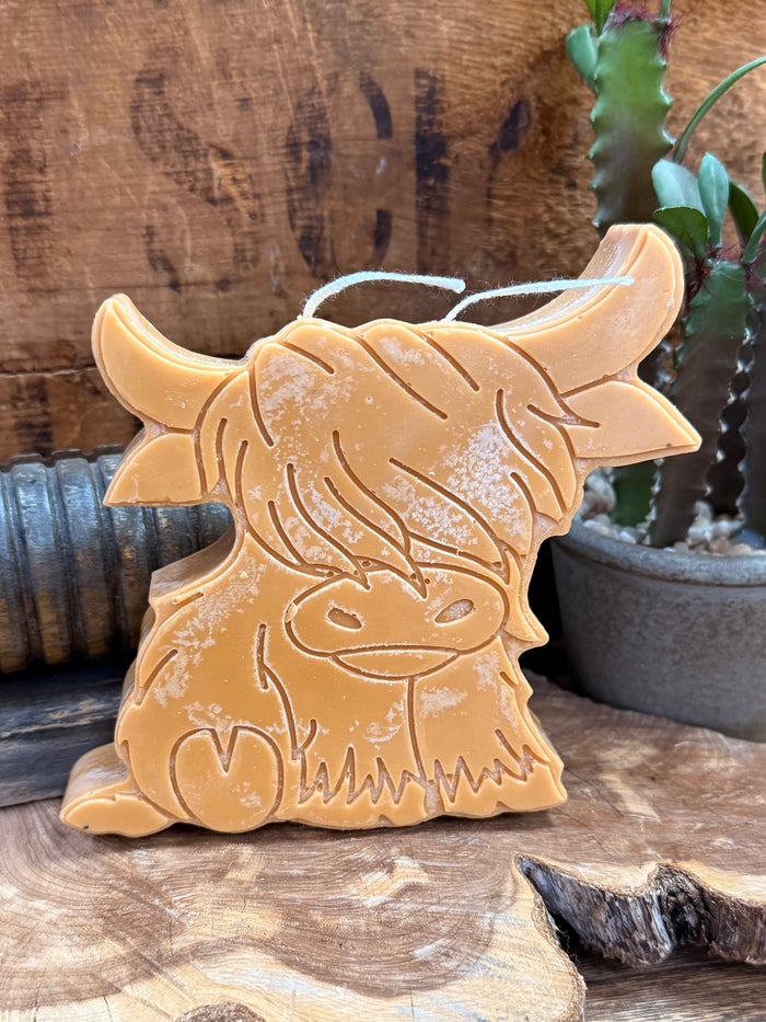 Gold highland cow candle close-up, detailed embossed face with wick