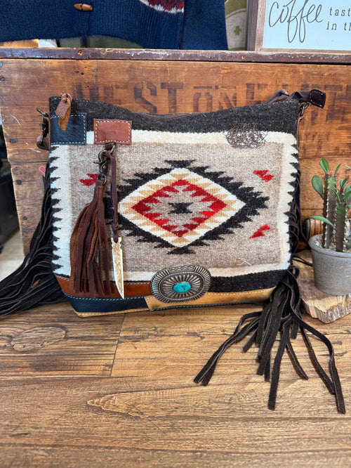 Woven wool crossbody purse with leather trim, geometric pattern, and long fringe tassels