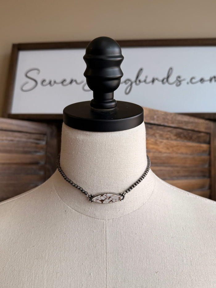 Stone pendant necklace with silver chain and oval pendant charm with light stone detailing