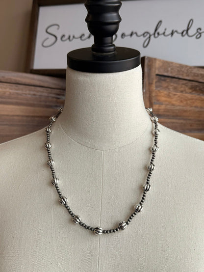 Pearl bead necklace on a mannequin, silver-tone beaded chain with rounded bead drops