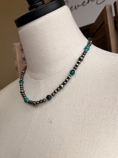 Turquoise stone bead necklace with silver-tone links, angled close-up