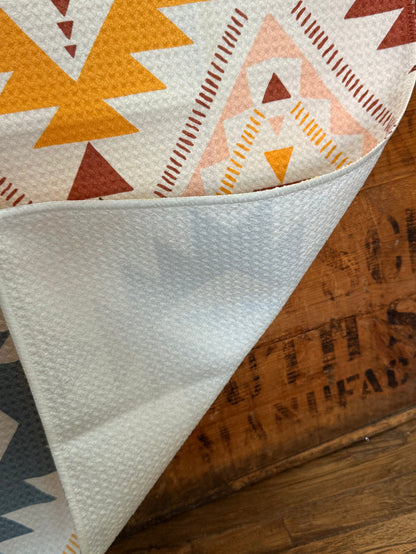 Cream towel corner with textured fabric and folded edge; multicolor Aztec print on top.