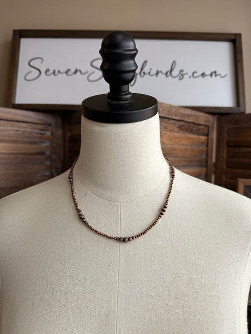Copper graduated bead necklace on bust mannequin, 18 in length.