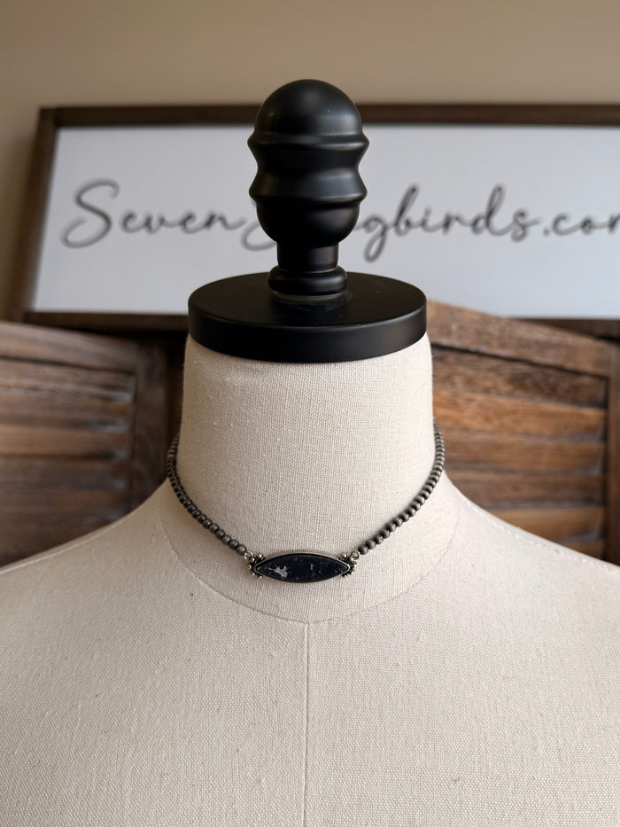 Stone pendant necklace with silver chain and centered oval dark pendant charm