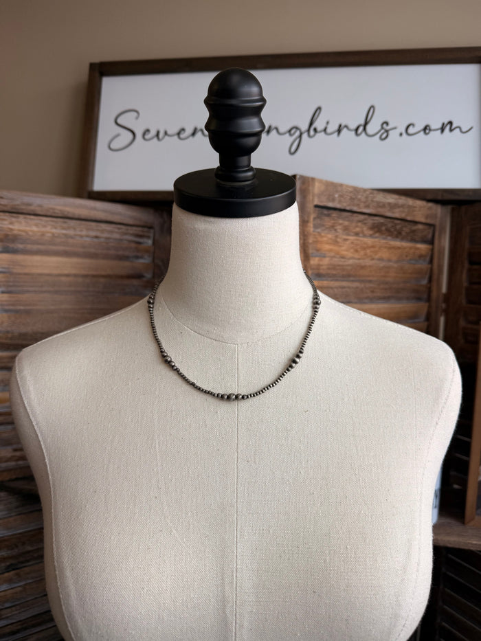 Graduated silver pearl necklace with graduated faux pearls on thin chain, worn on mannequin