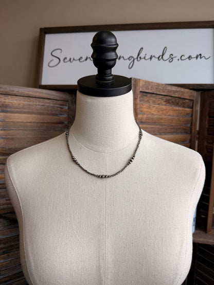 Graduated silver pearl necklace with graduated faux pearls on thin chain, worn on mannequin