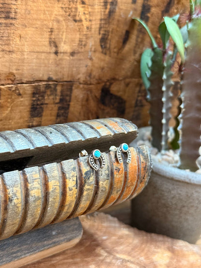 Sterling horseshoe stud earrings featuring turquoise stones and arched silver border