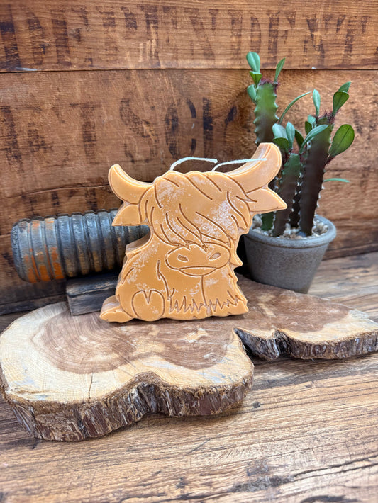 Gold highland cow candle with embossed face and horns, visible wick on top