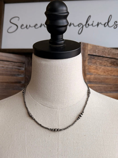 Graduated silver pearl necklace with small-to-large pearls along a metal chain, front view