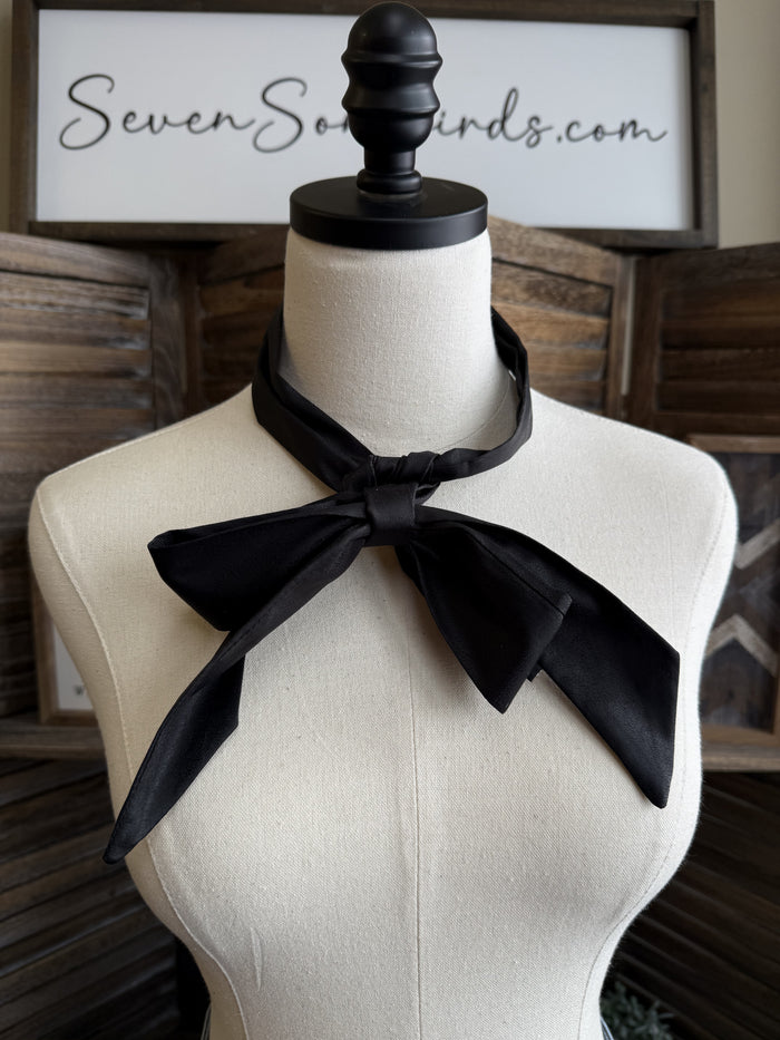 Black leather twilly scarf tied in a large bow at the neck on a mannequin
