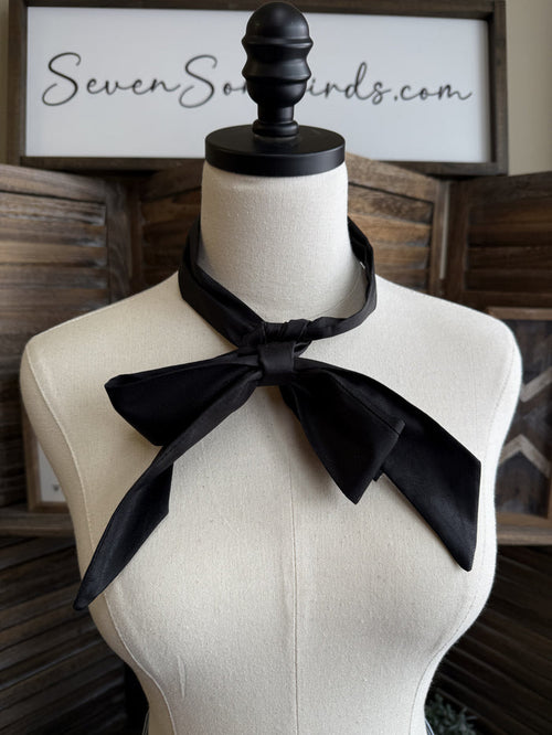 Black leather twilly scarf tied in a large bow at the neck on a mannequin