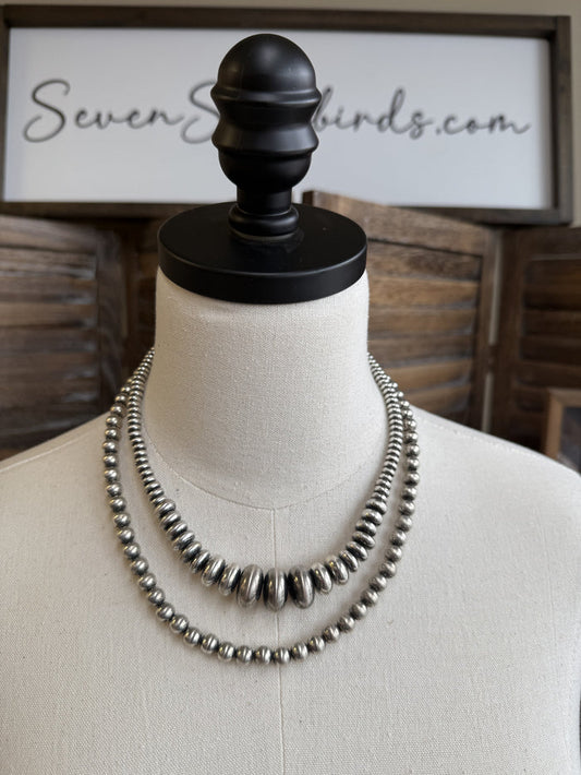 Double-layer shiny pearl necklace with metallic round beads on white mannequin