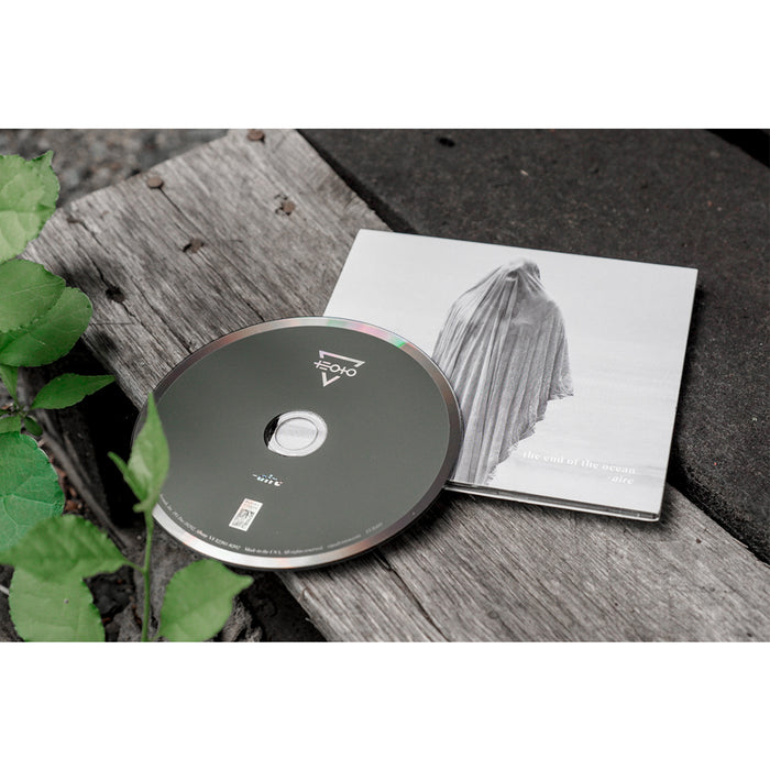 A CD by The End Of The Ocean sits on a weathered wooden surface next to its case, which shows a monochrome figure draped in cloth, suggesting redemption. Green leaves appear in the image’s corner.