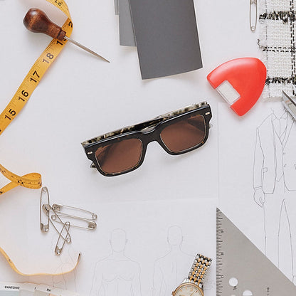 still life of emily in paris x diff eyewear featuring the alfie rectangle sunglasses with a truffle tortoise frame and deep brown lenses front view surrounded by designer tools
