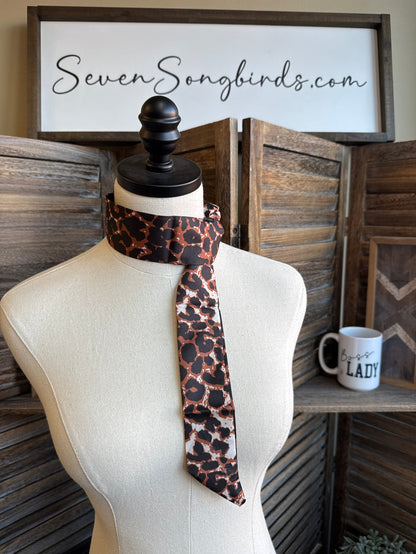 Animal print twilly scarf in brown, tan, and black, tied around a mannequin neck